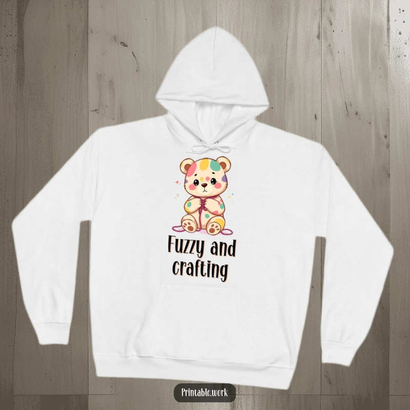 Funny hoodie with a content bear character knitting a colorful abstract pattern, perfect for staying warm and cozy.