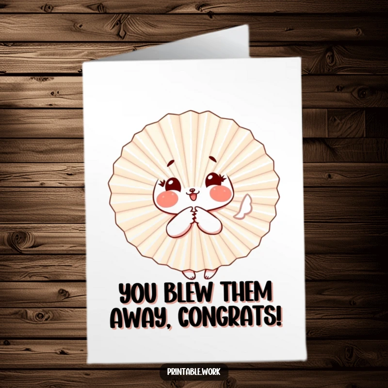 Funny free printable congratulations card featuring a paper fan character with rosy cheeks fluttering playfully to express joy.